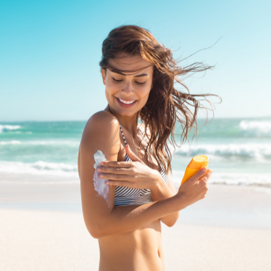 Moteris tepanti SPF 50 apsauginį kremą paplūdimyje